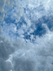 Stormy sky with dark, snowy clouds on a spring day. Clouds are floating across the sky. Dramatic clouds. Dark blue clouds swiftly floating across blue sky. Sky texture, abstract nature background.