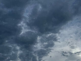 Stormy sky with dark, snowy clouds on a spring day. Clouds are floating across the sky. Dramatic clouds. Dark blue clouds swiftly floating across blue sky. Sky texture, abstract nature background.