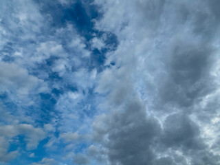 Stormy sky with dark, snowy clouds on a spring day. Clouds are floating across the sky. Dramatic clouds. Dark blue clouds swiftly floating across blue sky. Sky texture, abstract nature background.