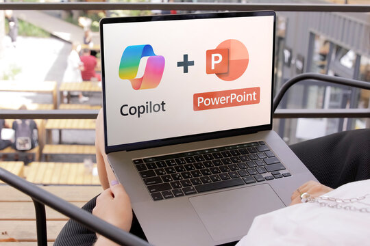 Woman using copilot in powerpoint on laptop outdoors