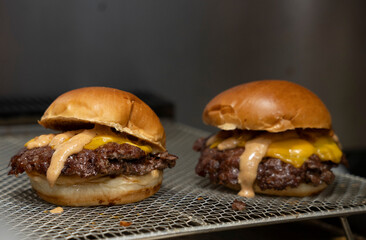 Close-Up of a Juicy Smash Burger with Special Sauce and Melted Cheese on Grill Rack..
