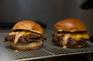 Close-Up of a Juicy Smash Burger with Special Sauce and Melted Cheese on Grill Rack..