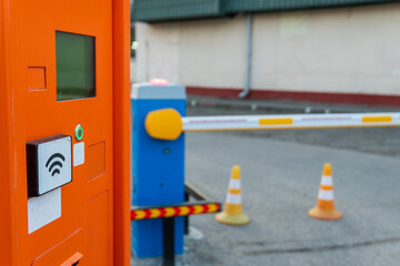 Orange automatic parking payment station with wireless payment sensor, traffic cones, and a parking...