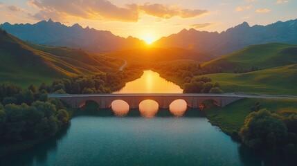 Scenic mountain valley landscape with arch bridge at sunset.