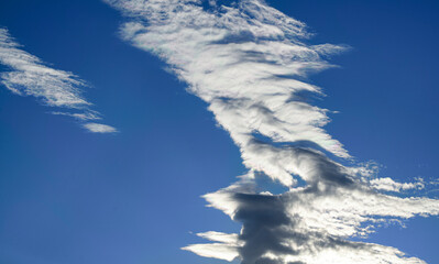 Dramatic formation of high-altitude clouds against a deep blue sky. Iridescent edges highlight the...