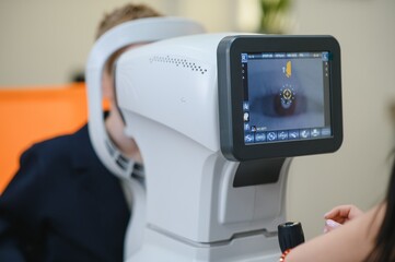 Ophthalmologist performing vision diagnostics on child patient using autorefractor
