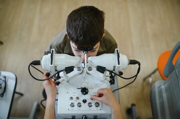 Ophthalmologist examining child's vision with modern equipment in clinic
