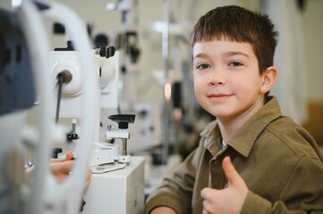 Boy showing thumb up during eye exam at ophthalmology clinic