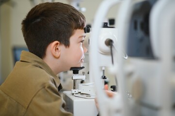 Boy undergoing vision diagnostics with ophthalmological equipment in clinic