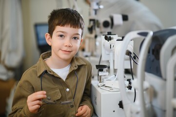 Boy holding eyeglasses during vision diagnostics in ophthalmology clinic