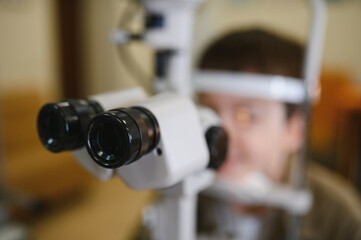 Ophthalmologist performing vision diagnostics on child patient in clinic