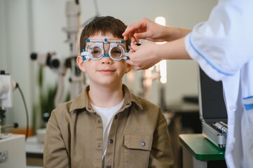 Ophthalmologist examining eyesight of child with trial frame in clinic