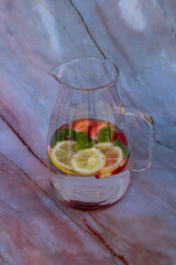 Glass pitcher of strawberry, lemon and mint infused water.