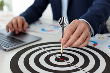 Man with dart aiming at dartboard while working indoors, closeup
