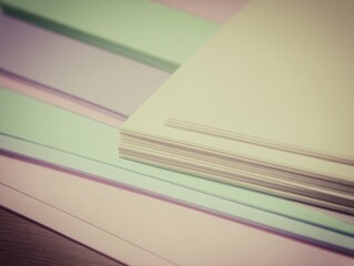Colorful layers of pastel paper stacked creatively on a wooden surface, showcasing vibrant hues and textures ideal for art, crafts, and design projects.