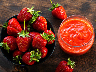 Fresh strawberries in a bowl on a wooden table and strawberry dessert with sugar