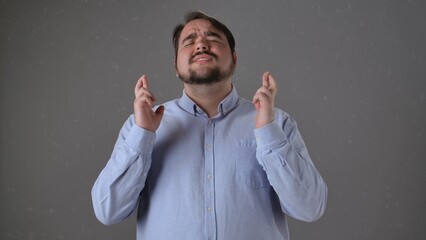 Man with Fingers Crossed Hoping for Good Luck in Studio Portrait