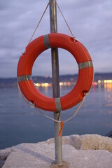Red life preserver is hanging from a metal pole