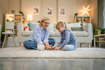 Fototapeta premium grandmother and grandchild save money together at piggy bank