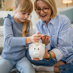 grandmother and grandchild save money together at piggy bank
