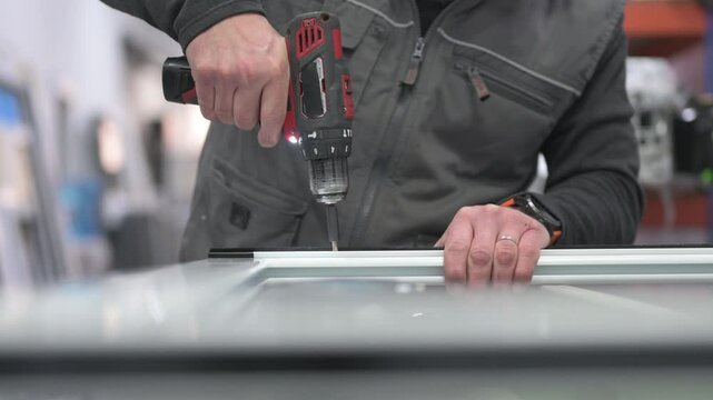 Construction worker using cordless drill on aluminum window frame