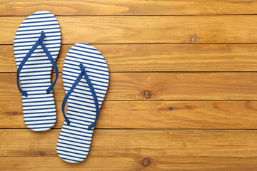 Striped blue flip flops on wooden background, top view
