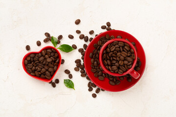 Roasted coffee beans with leaves on concrete background,top view