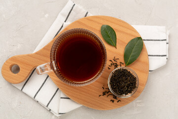 Cup of tea with dry and fresh leaves on concrete background, top view
