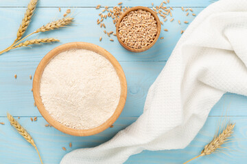 Bowl with spelt flour on wooden background, top view