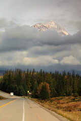 Sunny tip of Pyramid Mountain jutting from the clouds as background for a tract of the Highway...