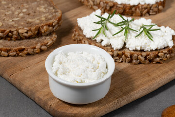 Delicious rye bread topped with creamy cheese and fresh herbs on a rustic wooden board