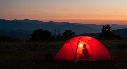 Camping under a vibrant twilight sky, nestled amid the majestic mountains, a red tent casts a warm, inviting glow.