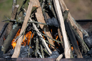 The old barbecue grill is set up in a country yard . Barbecue grill with smoke. Barbecue on the fire. Wood arranged in the shape of a campfire burns on a grill. Preparing barbecue in nature.