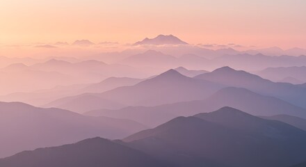 Layered mountain ranges appear in hazy, pastel-toned hues, the farthest peak veiled in soft, light-colored clouds during the golden hour.