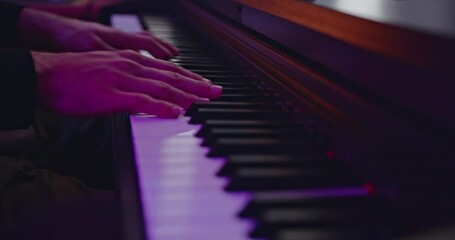 Musician's hands play a piano keyboard, illuminated by purple studio lights, conveying emotion and musical talent. - Powered by Adobe