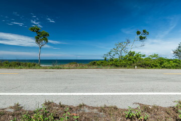 Side view of asphalt road with sea and beautiful blue sky.