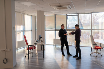Two Caucasian men talking at work in the office. 