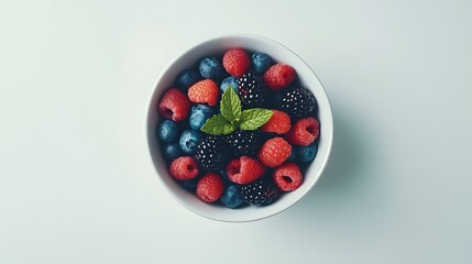 A bowl of fresh berries including raspberries, blackberries, and blueberries with a sprig of mint