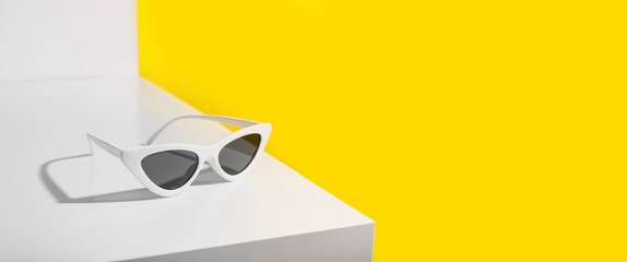 Stylish sunglasses on table against yellow background with space for text