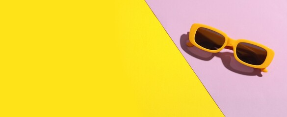 Stylish sunglasses on color background with space for text, top view