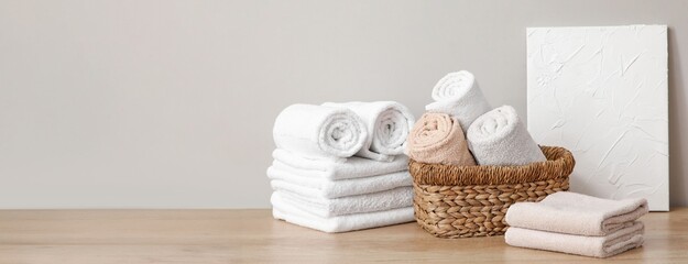 Wicker basket and clean soft towels on table in bathroom. Banner for design
