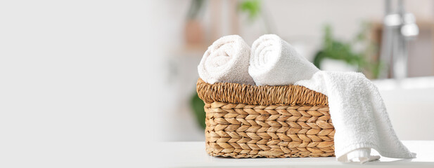 Wicker basket with clean towels on table in bathroom. Banner for design