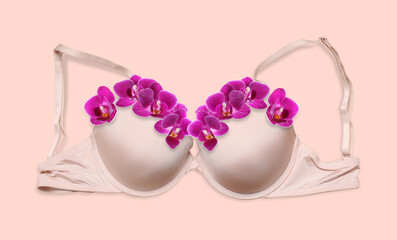 Beautiful bra with orchid flowers on beige pink background, top view. Banner design