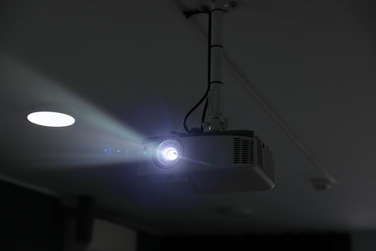 Modern video projector mounted on ceiling working indoors