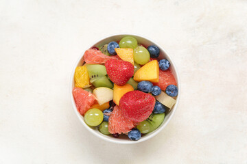 Bowl of fresh fruit salad on light background