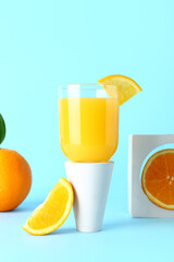 Decorative podium with glass of fresh orange juice on blue background