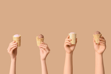Female hands with different sweet ice-cream in waffle cups on brown background
