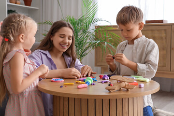 Cute little children with their mother sculpting from plasticine at home