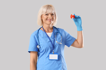 Female endocrinologist with thyroid gland model on light background