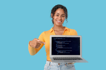 Young African-American QA engineer pointing at laptop with programming code on blue background